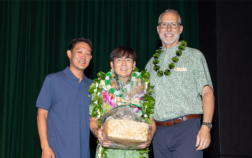 three men wearing leis, presenting gift