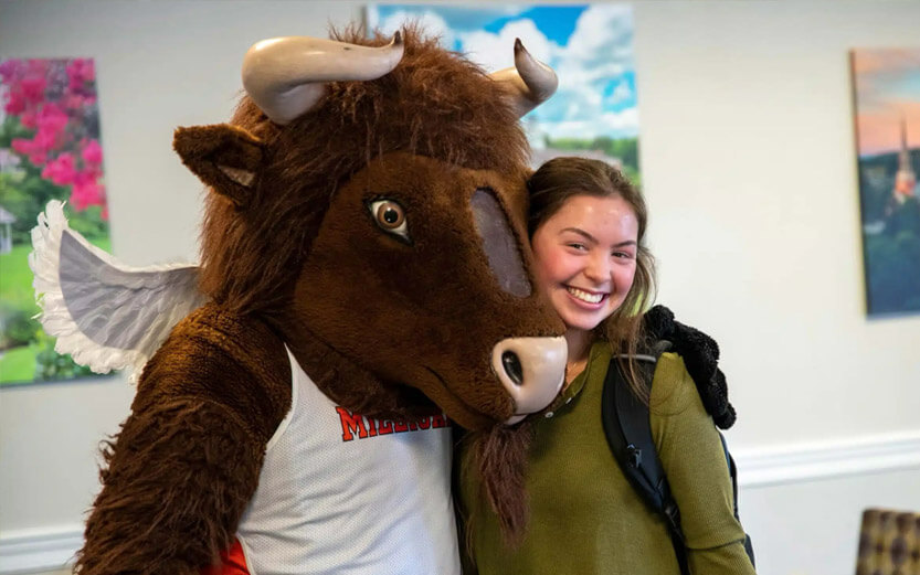 the Milligan school mascot hugging a student who is smiling