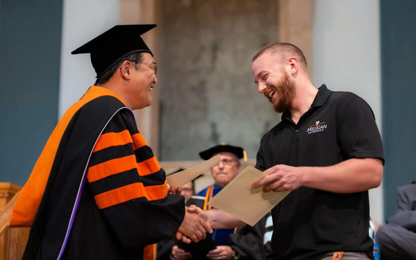a student shaking the hand of a school dean during graduation