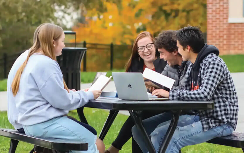 a group of students sitting outside studying and laughing