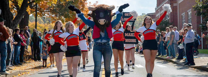 school cheerleaders and a bull mascot walking and cheering in a parade
