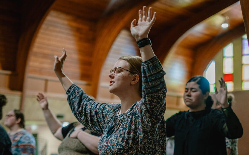 woman with arms raised singing in church