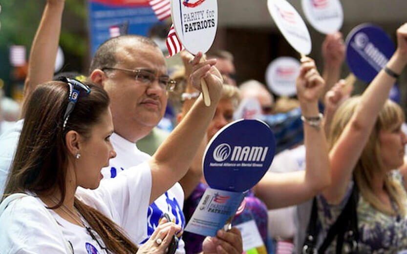 a group of NAMI advocates holding signs at an event outdoors