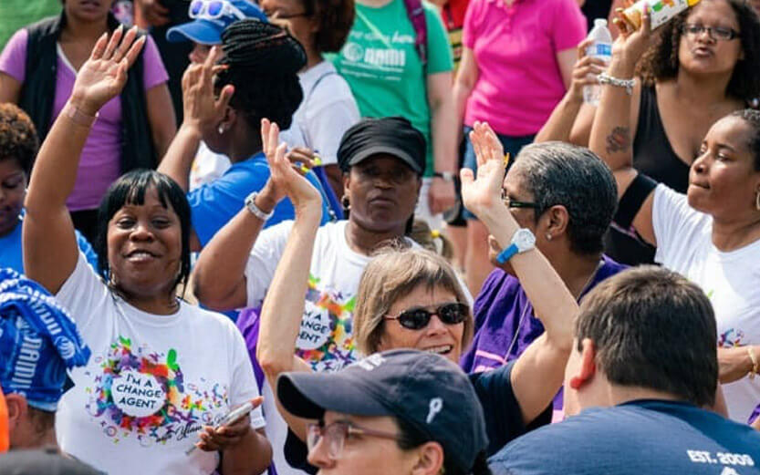 a group of NAMI supporters with focus on a woman with her hand up smiling