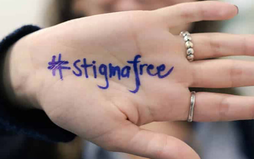 closeup of the palm of a hand with the hashtag stigmafree written in blue marker