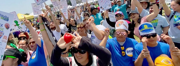 a crowd of people cheering and holding signs at a NAMI event