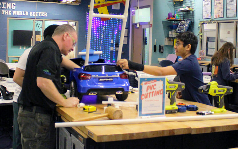 a teacher and students working on a gobabygo car