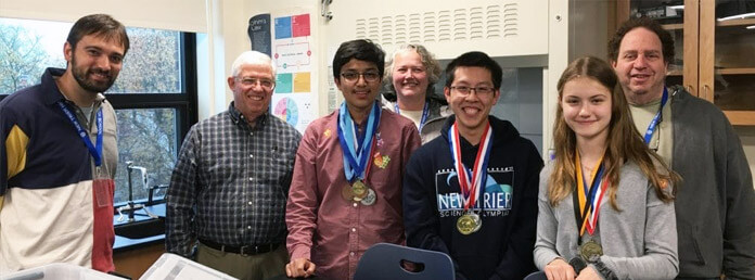 students and teachers in a classroom wearing medals around their necks