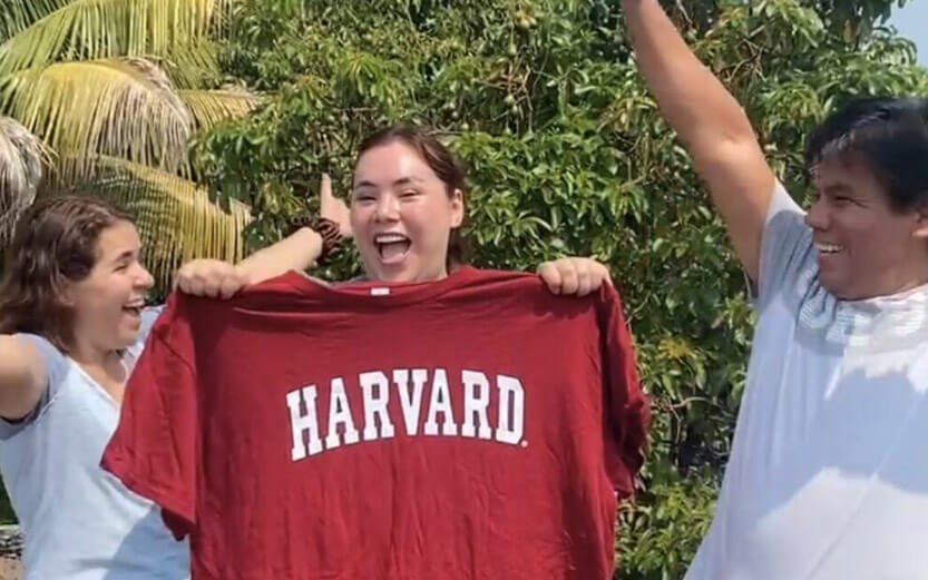 an excited student holding a red Harvard tshirt