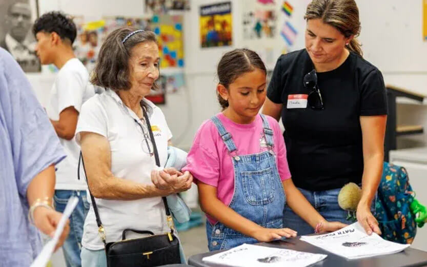 a young student wearing overalls with her grandmother looking through math papers