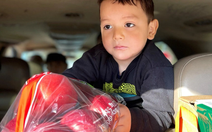 a young boy receiving a bag of apples