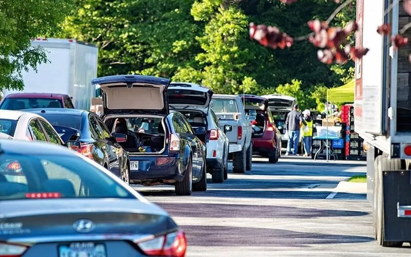 a line of cars with trunks open waiting to receive food