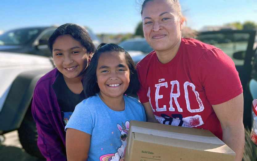 a mother and her two daughters recieving a box of food