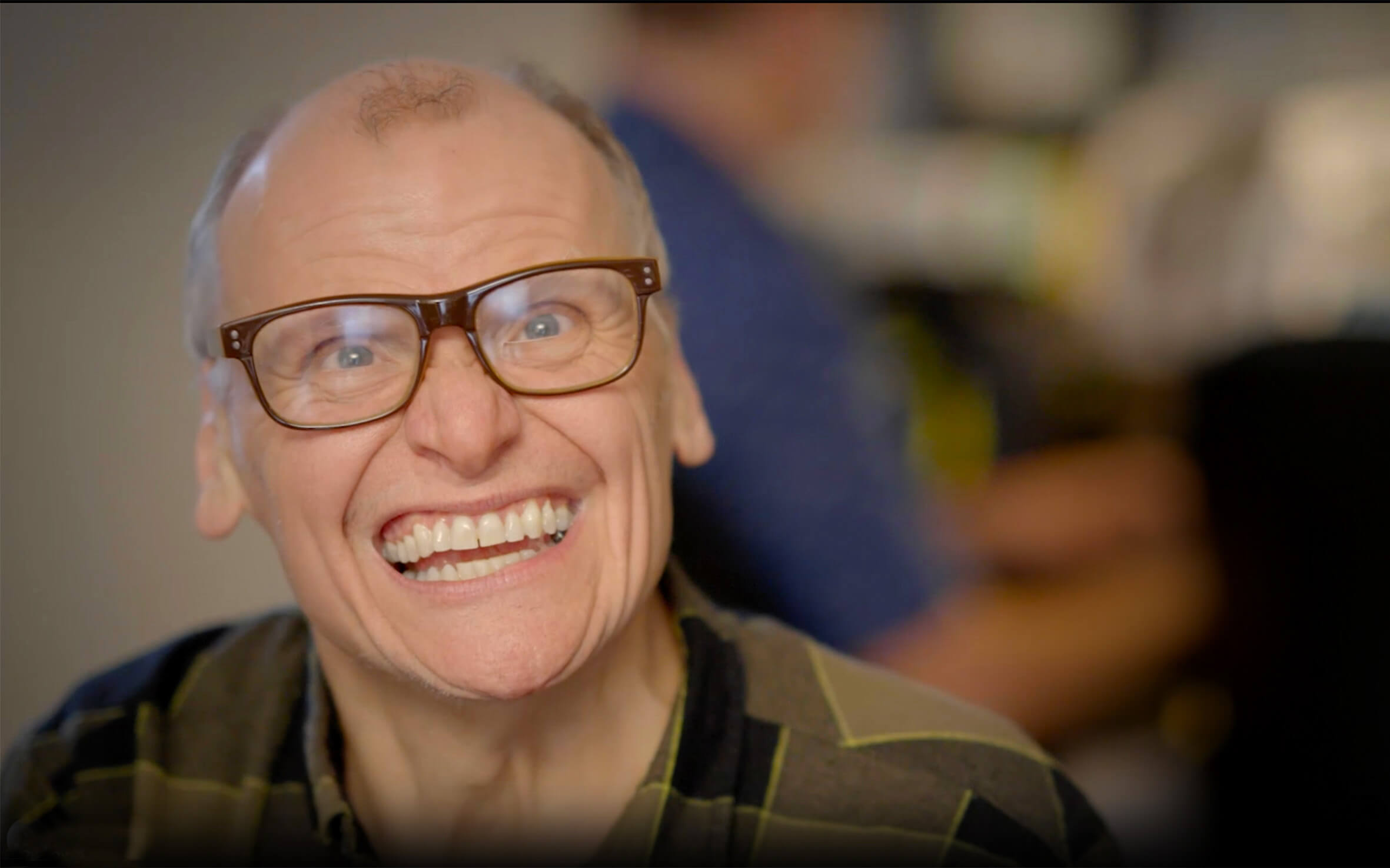 man with glasses and a big smile