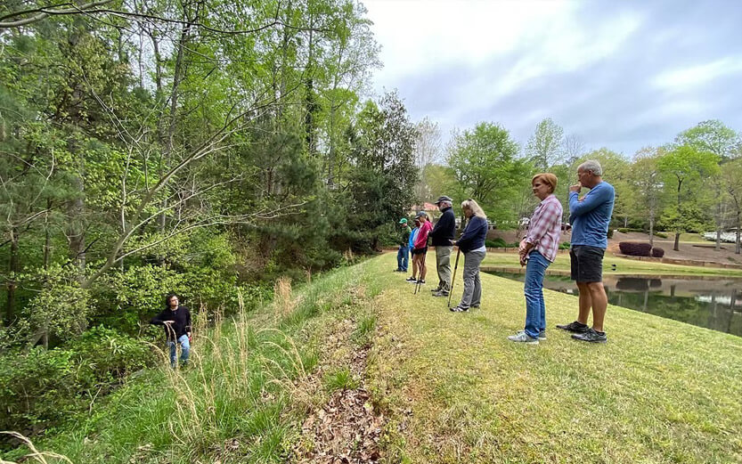 group of people on the bank of a river listening to a guide