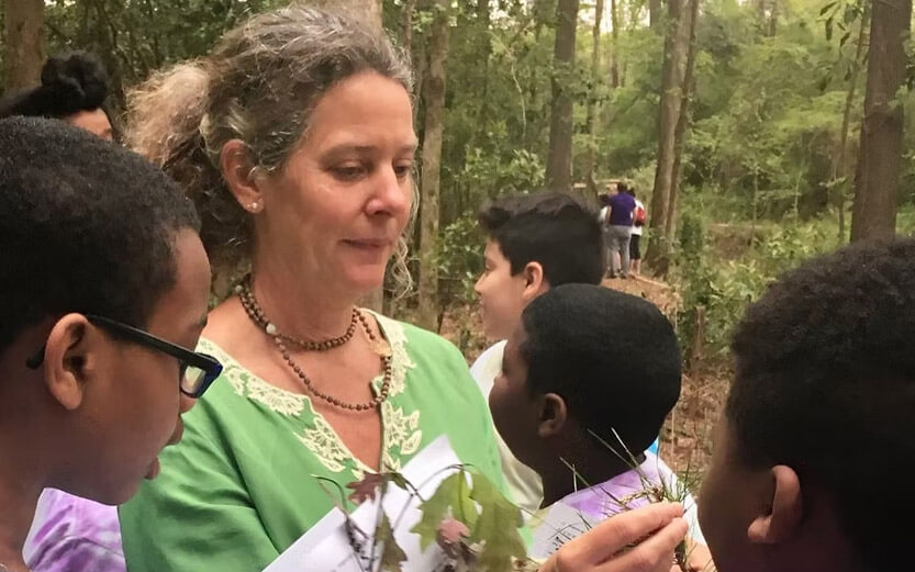 teacher showing kids plants near a river