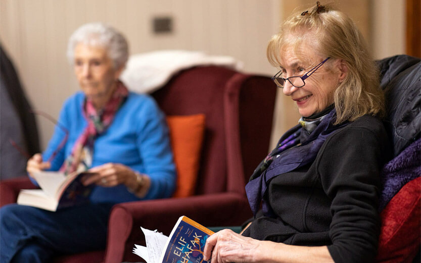 two senior women discussing a book