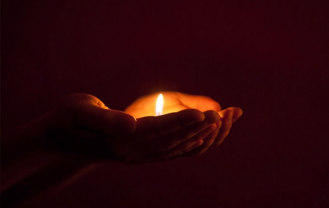 cupped hands holding candle