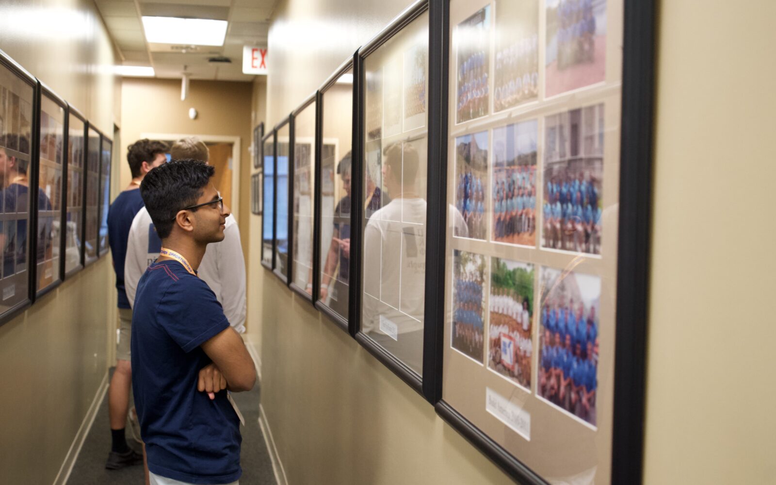 Pi Kappa Phi member in a hallway, looking at group photos from previous years.