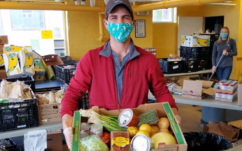 a volunteer showing a box filled with produce