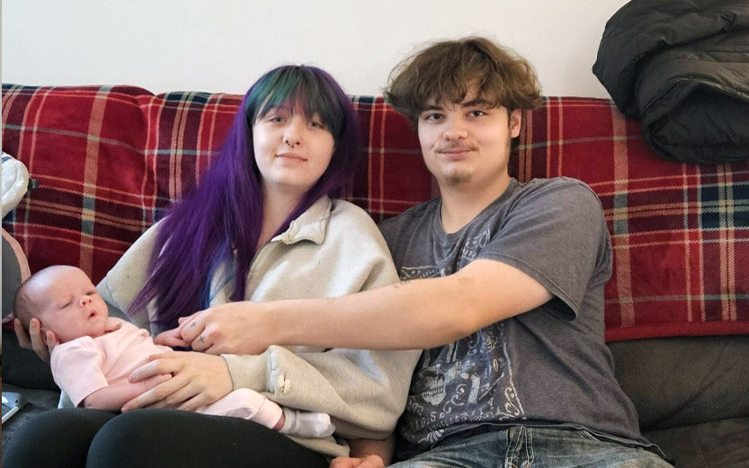 new mom and dad sitting on a couch with their newborn