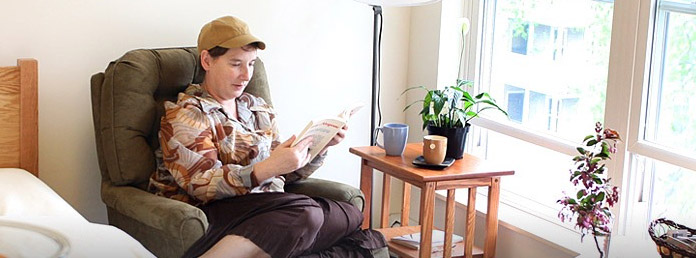 woman sitting in a chair in temporary housing reading a book