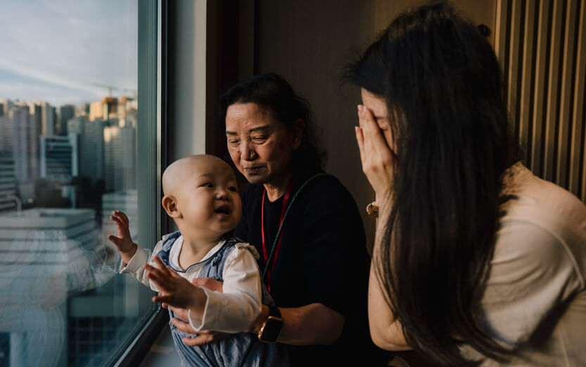 a mother and grandmother play peekaboo with a toddler
