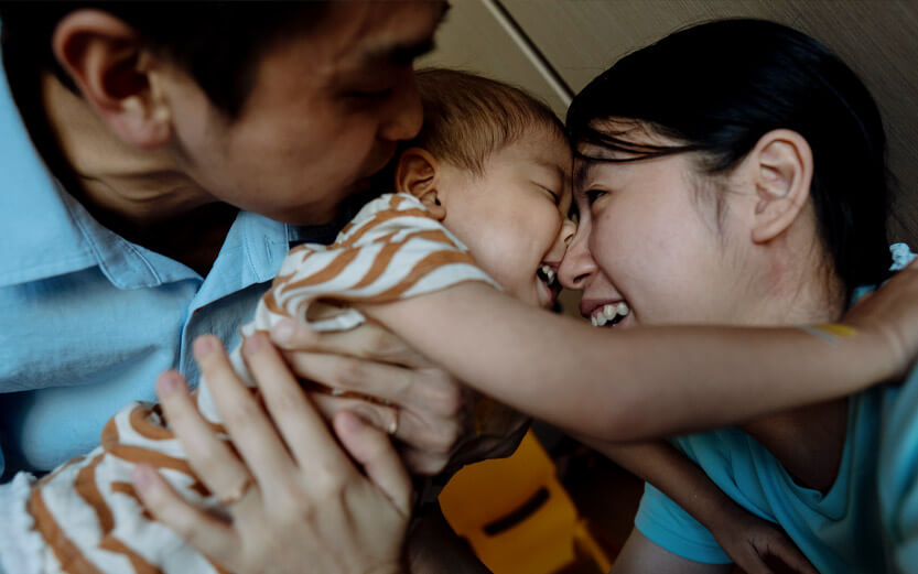 a father holds a toddler as he laughs with his sister