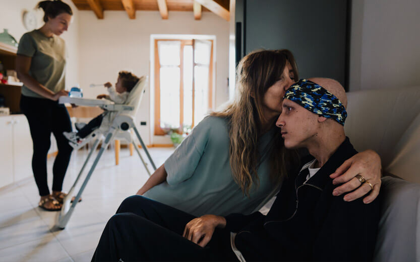 a mother kissing her ill son on the forehead
