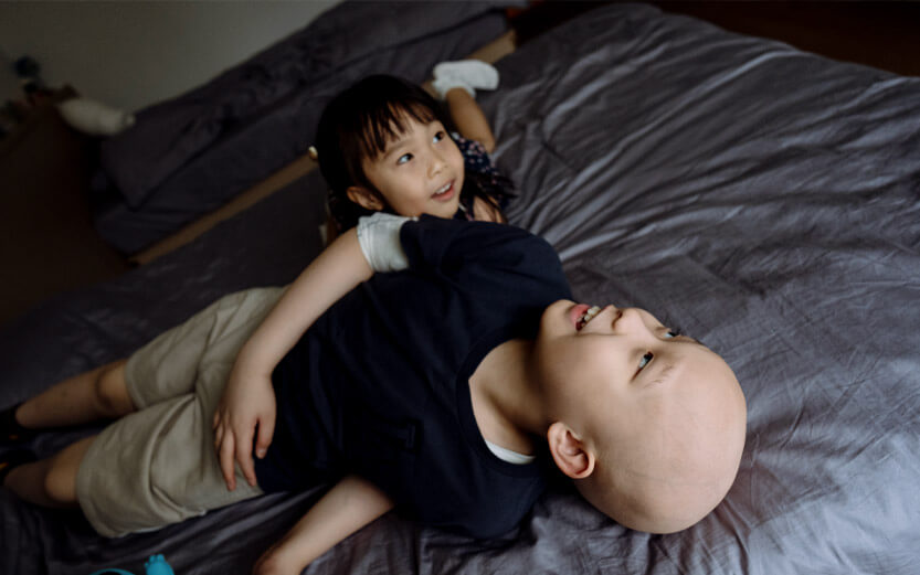siblings playing and laughing on a bed