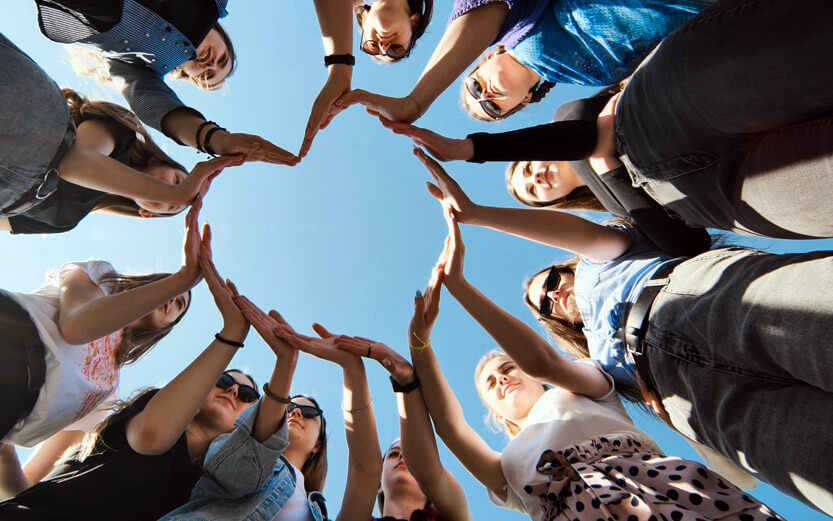 view from below of a group of women making one big heart with their hands