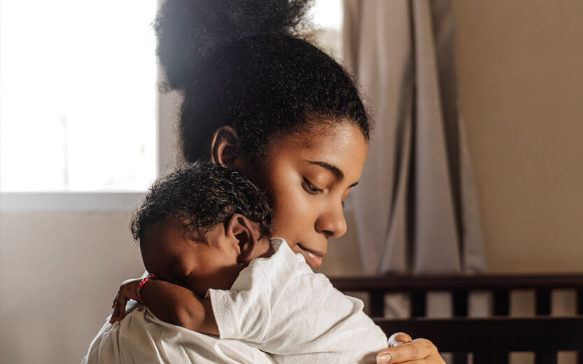 profile of a young mother holding her newborn over her shoulder