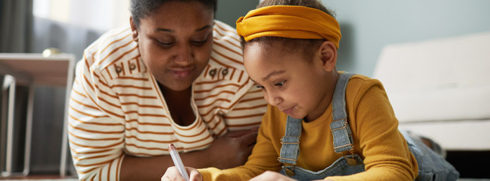 a mother watching her young daughter draw