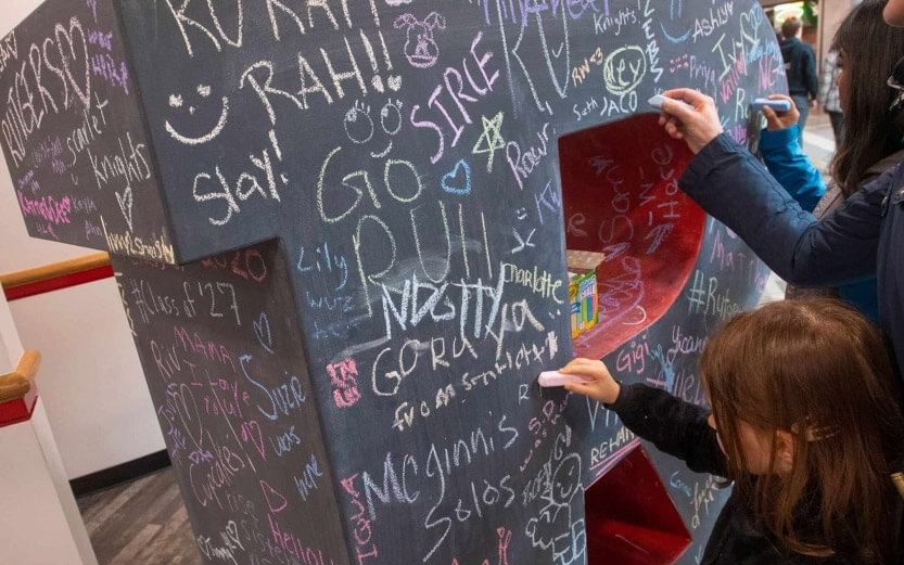 Rutgers students writing words of encouragement on a chalkboard R