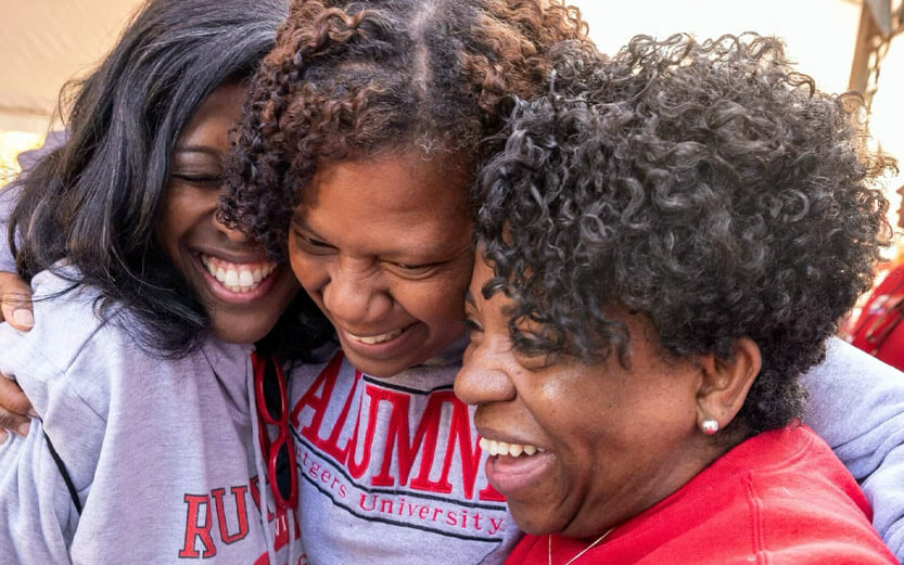 three Rutgers alumni hugging each other