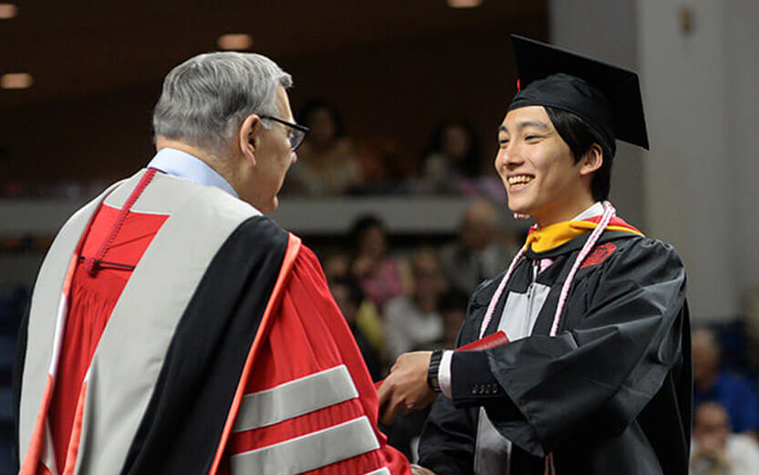 asian student receiving their diploma at graduation ceremony