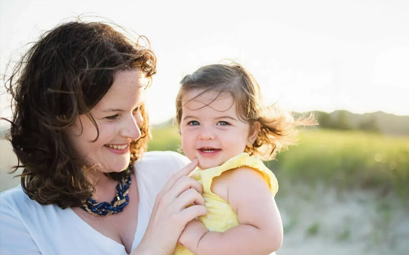 a woman holding her toddler daughter smiling
