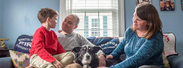 a family sitting on the couch with their dog