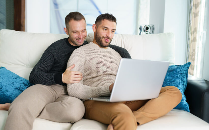 gay couple looking at a laptop in living room