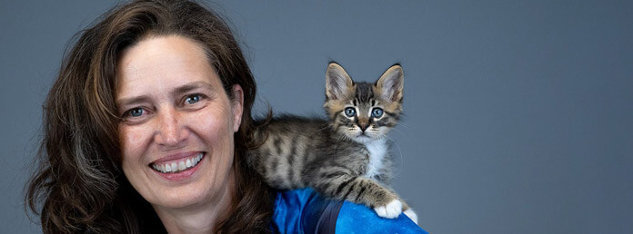 woman with brown hair and a tabby sitting on her shoulder