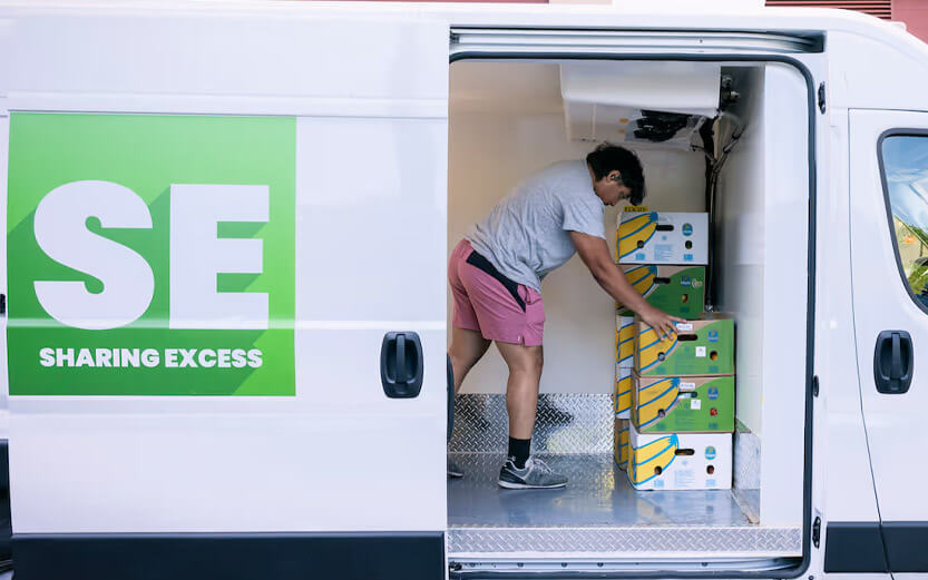 a man stacking boxes of produce in a van