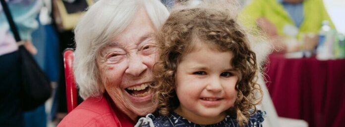 An elderly woman holding a girl on her lap