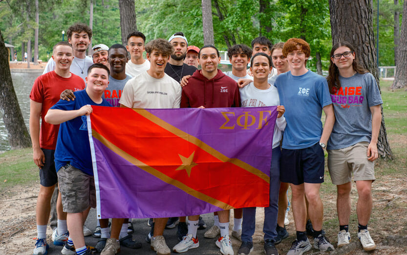 Sigma Phi Epsilon group outdoors holding up their flag