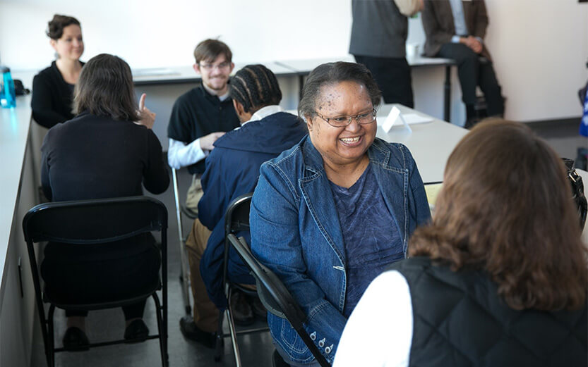 People seated in pairs, talking and smiling during a group event