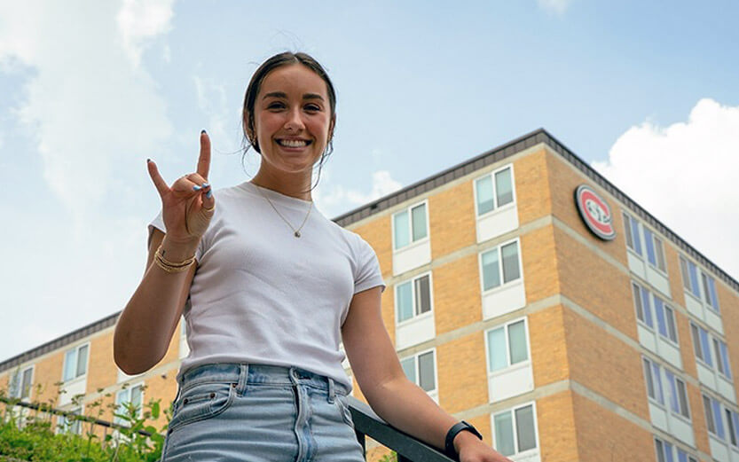 a student in front of a dorm building
