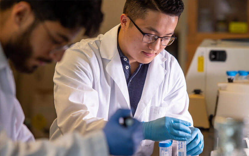 a student wearing a white coat in a research lab