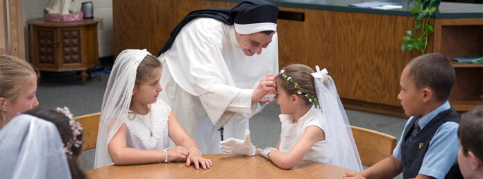 a nun blessing a young girl