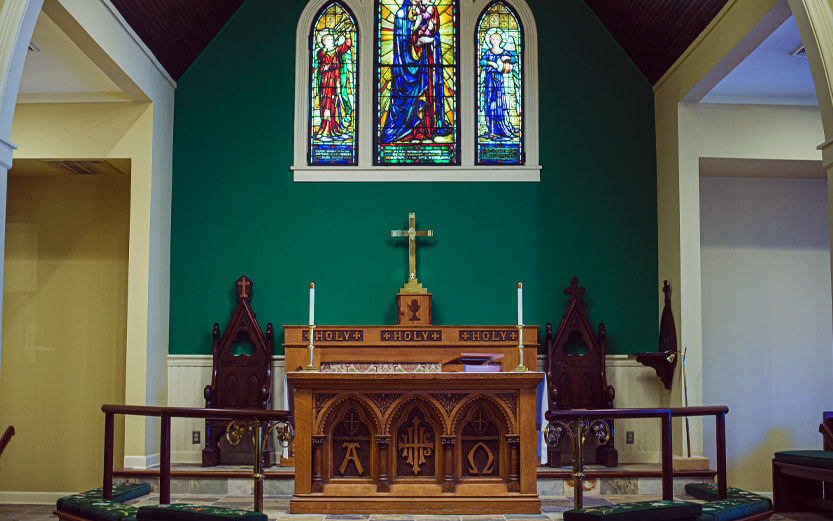 inside a chapel with stained glass and a carved wood altar