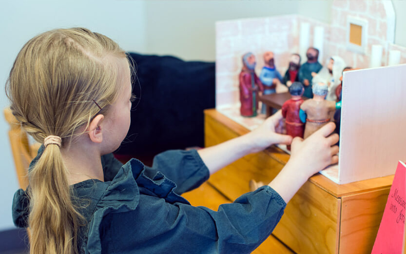 young girl playing with religious figurines