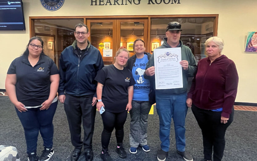 group of people outside a hearing room holding up a certificate